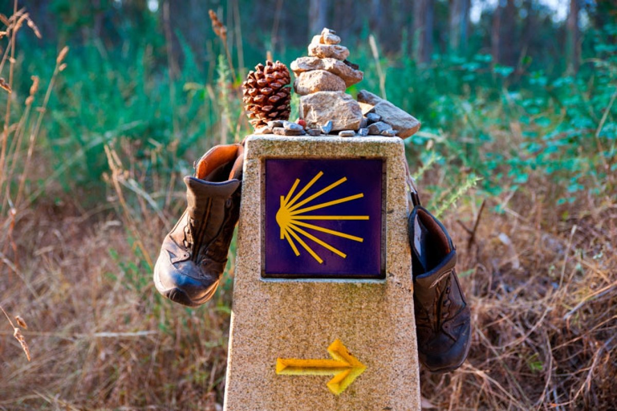 Hito del Camino de Santiago con concha y botas de peregrino